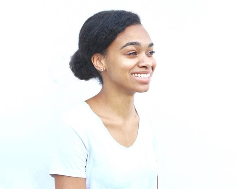 Monique Burton smiling in front of white wall.