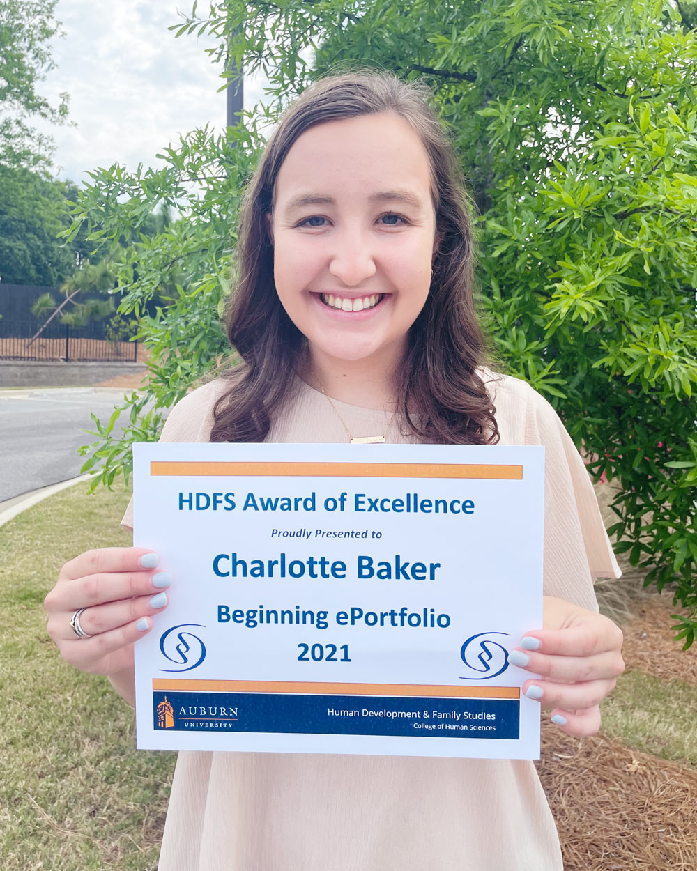 Charlotte Baker holding a plaque of her Beginning ePortfolio award.