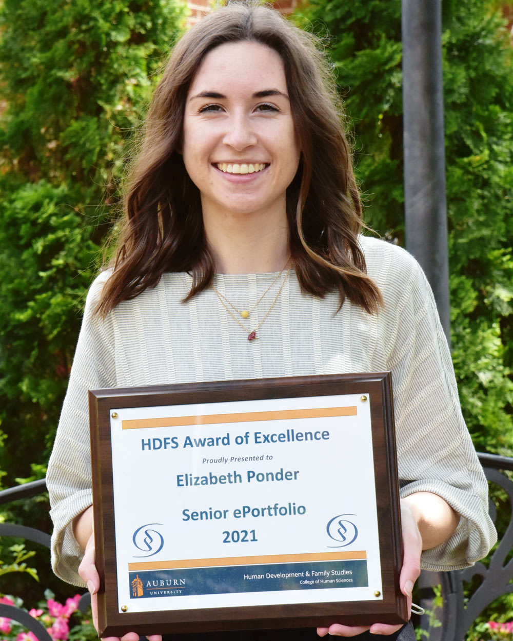 Elizabeth holding a plaque of her Senior ePortfolio award.