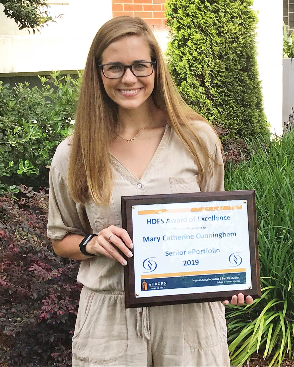 Mary Catherine holding a plaque of her Senior ePortfolio award.